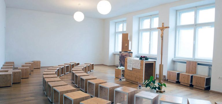 Celkový pohľad na priestor kaplnky. Priestorové obmedzenie pôvodnej školskej učebne bolo pretvorené v otvorený, čistý priestor s jasne čitateľným zariadením.