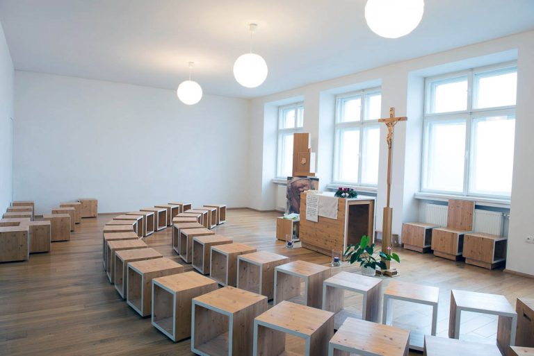 Celkový pohľad na priestor kaplnky. Priestorové obmedzenie pôvodnej školskej učebne bolo pretvorené v otvorený, čistý priestor s jasne čitateľným zariadením.